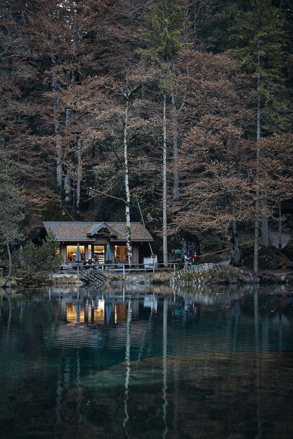 Een houten lodge gloeit bij een donker meer in de schemering.